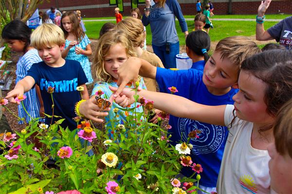 students in a flower garden with butterflies